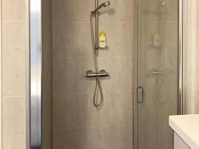 a shower with a glass door with a shower head at 8 person holiday home in Urangsvåg in Ervik