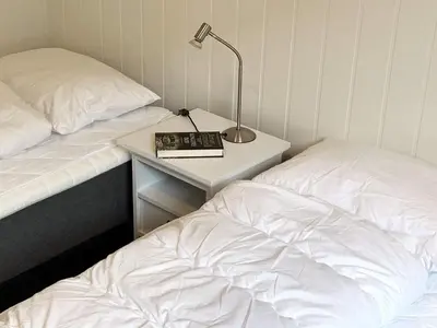 a bedroom with two beds and a night stand with a lamp at 8 person holiday home in Urangsvåg in Ervik