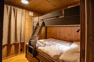 a bunk bed in a wooden room with a ladder at Trysiltunet 10B in Trysil