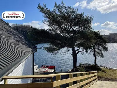 a tree on the side of a house next to the water at 6 person holiday home in Rubbestadneset in Rubbestadneset