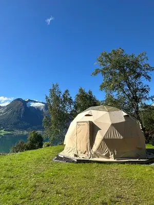 a tent on a grassy hill with a mountain in the background at Vollsnes Glamping in Stryn