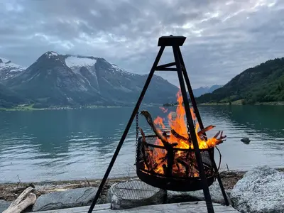 a fire in a basket next to a body of water at Vollsnes Glamping in Stryn