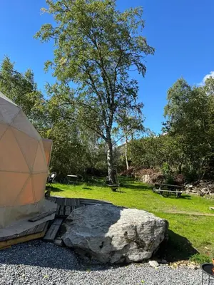 a tent sitting next to a rock and a tree at Vollsnes Glamping in Stryn