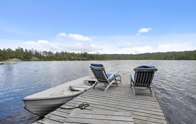two chairs and a boat on a dock on a lake at Awesome Home In Flesberg With Sauna in Flesberg