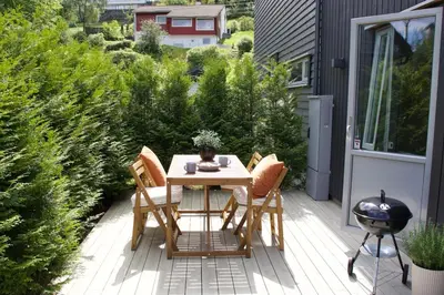 a patio with a table and chairs and a grill at Moderne hus - sentralt, rolig med gratis parkering in Bergen