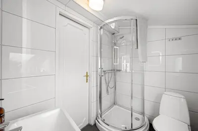a white bathroom with a shower and a toilet at Charming apt in the centre of Bergen in Bergen