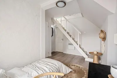 a bedroom with white walls and a stair case at Charming apt in the centre of Bergen in Bergen