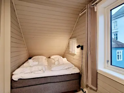 a small bed in a room with a window at Historic charm in the heart of Bergen in Bergen