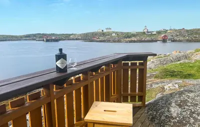 a bottle of wine sitting on a wooden railing next to a river at Nice Home In Sauøya With House Sea View