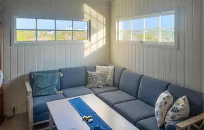 a living room with a blue couch and a table at Nice Home In Sauøya With House Sea View