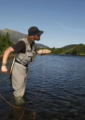 a man is standing in the water holding a line at Brand new house close 2 Skiresort in Hemsedal