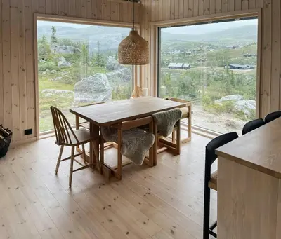 a dining room table with chairs and a large window at Architect-Designed Cabin With Views Of Sigdal in Eggedal