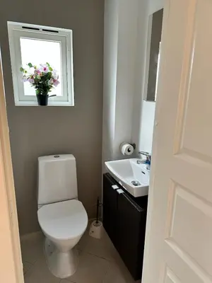 a bathroom with a toilet and a sink and a window at Cozy house with a sea view in Knarrvika