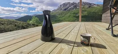 a black vase sitting on a wooden deck with a cup at Modern Lines And Coziness In Hemsedal in Hemsedal
