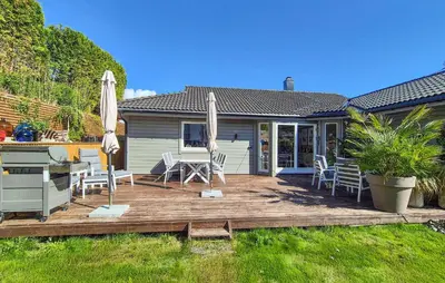 a deck with chairs and umbrellas in front of a house at Beautiful Home In Bjørøyhamn With House Sea View in Nord Bjørøy