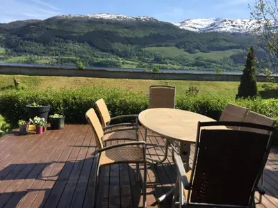 a table and chairs on a deck with snow covered mountains at Koselig hus med flott utsikt in Vossevangen