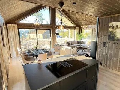 a kitchen and living room with a table and a couch at Luxury holiday home, skiing, sauna, remote office in Nesbyen