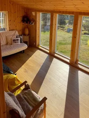 a living room with windows in a wooden cabin at Family Cabin At Birkebeiner Slopes In Sjusjøen in Sjusjøen