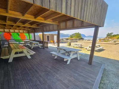 a group of picnic tables on a wooden deck at 6 person holiday home in Sørbøvåg in Sørbø