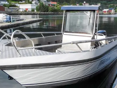 a white boat is docked at a dock at 6 person holiday home in Sørbøvåg in Sørbø