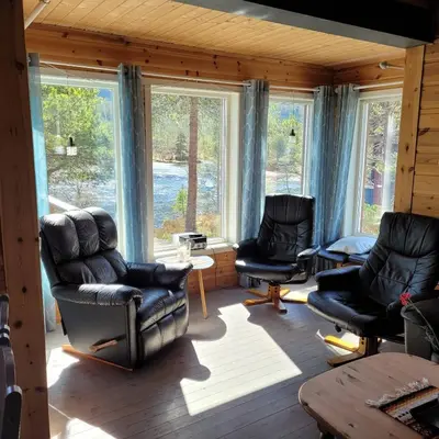 a living room with chairs and a table and windows at Hytte ved Gaularfjellet in Viksdalen