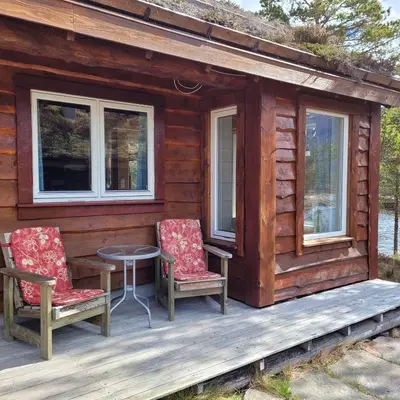 a cabin with two chairs and a table on a deck at Hytte ved Gaularfjellet in Viksdalen