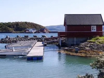 a dock with boats in the water next to a building at Seaside Retreat with Boats & Fishing in Brekstad