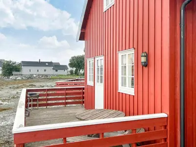 a red house with a wooden deck on the side of it at Seaside Retreat with Boats & Fishing in Brekstad