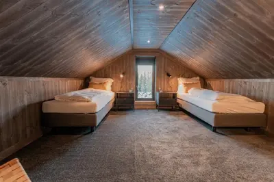 two beds in a room with wooden walls at Ski centre, sauna, hot tub