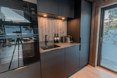 a kitchen with black cabinets and a sink at Ski centre, sauna, hot tub