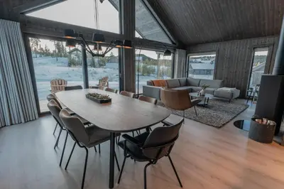 a dining room and living room with a table and chairs at Ski centre, sauna, hot tub