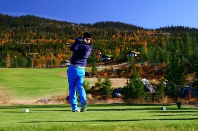 a man swinging a golf club on a golf course at Ski centre, sauna, hot tub
