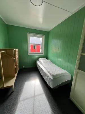 a green room with a bed and a window at Martini Fishing Camp in Lauvsnes