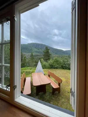 a picnic table and two benches outside a window at Small cabin at Seljestad in Utsikten