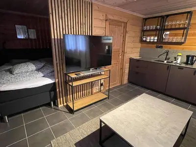 a living room with a large television and a kitchen at Small cabin at Seljestad in Utsikten