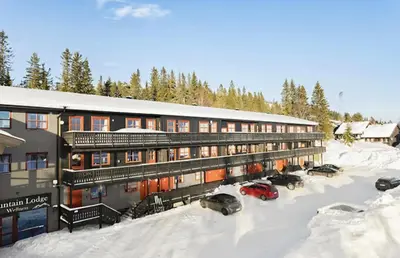 a building with cars parked in the snow at Mountain apartment Norefjell Ski in ski out in Surteberg