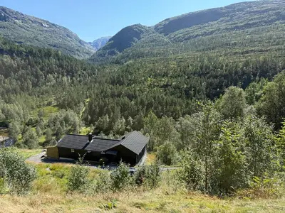a cabin in the middle of a valley with mountains at Fossen bratte chalet in Eikedalen