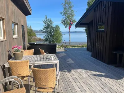 a wooden deck with a table and chairs on it at Cottage by the lake in Namsos in Fosslandsosen