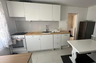 a kitchen with white cabinets and a sink and a refrigerator at Koselig 3 roms leilighet på Rjukan in Øverland