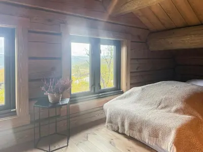 a bedroom with a bed and two windows at Modern Family Cabin Near Kikut In Geilo in Geilo