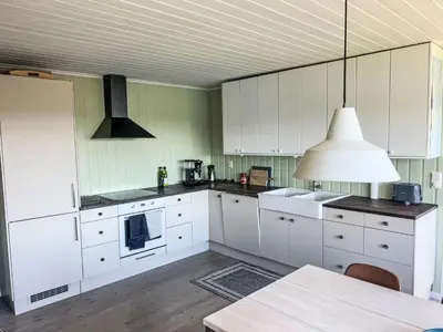 a kitchen with white cabinets and a table and a lamp at Holiday Home Lauvlid Cottage by Interhome in Tysnes