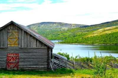 an old barn next to a body of water at Hyggelig fiskebu ved Langrumpa fiskevann in Venabygd