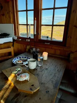 a wooden table with a cutting board and a window at Hyggelig fiskebu ved Langrumpa fiskevann in Venabygd