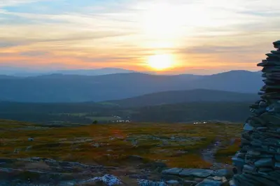 a sunset from the top of a mountain with the sun setting at Hyggelig fiskebu ved Langrumpa fiskevann in Venabygd