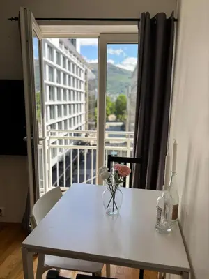a table with a vase of flowers on it with a window at Stay in the middle of Bergen city centre! in Bergen