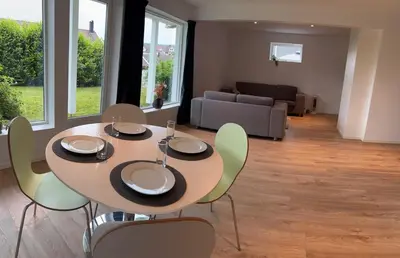 a dining table and chairs in a living room at Large and bright apartment, perfect base in autumn in Ålesund