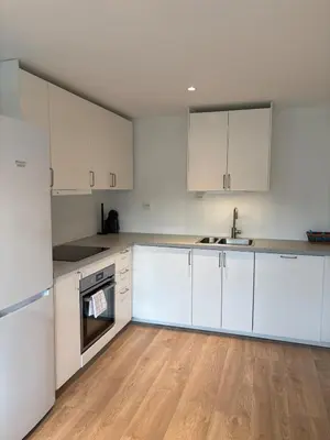 an empty kitchen with white cabinets and wooden floors at Large and bright apartment, perfect base in autumn in Ålesund