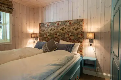 a bedroom with two beds and a headboard and two lamps at Valdreshytte med peis Klassisk og lun stil in Aurdal