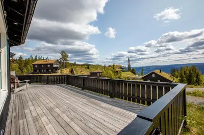 a wooden deck with a bench on top of a house at Valdreshytte med peis Klassisk og lun stil in Aurdal