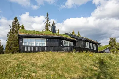 a black house on a hill with a tower at Valdreshytte med peis Klassisk og lun stil in Aurdal
